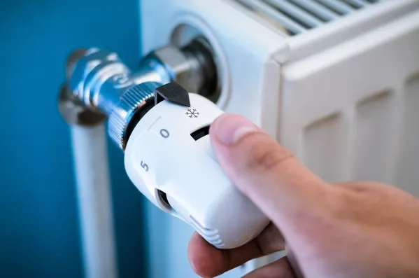 Person dreht Heizkörperthermostat ab