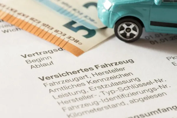 Autoversicherung, Geldscheine und ein Spielzeugauto in Nahaufnahme