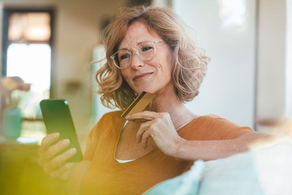 Frau benützt Kreditkarte und Smartphone