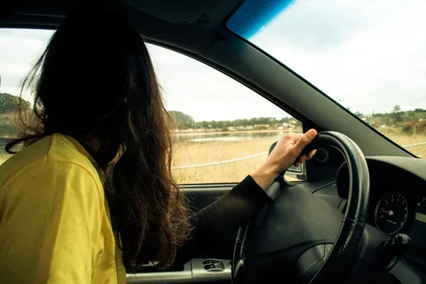 Frau blickt im Auto beim Spurwechsel über die Schulter